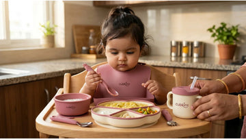 Indian baby using Cubkins 7-Piece Silicone Baby Feeding Set — suction plate, bendable spoon and sippy cup on highchair tray