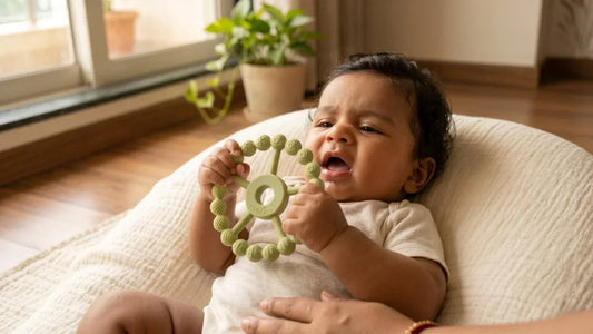 : Indian 4-month-old baby holding BIS-certified silicone ring teether in both hands — bright Mumbai apartment, natural light