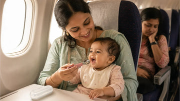 Indian mother feeding baby with stainless steel spoon in airplane during trip