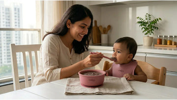 Indian mother spoon-feeding 7-month-old baby khichdi from silicone suction bowl at home