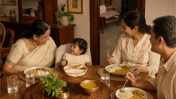 Indian toddler at family mealtime with grandparents — eating dal-rice from silicone suction plate at dining table