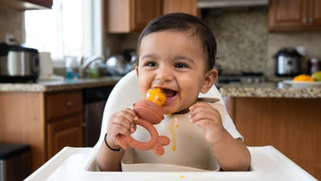 Indian baby using a Cubkins apricot silicone fruit feeder with mango