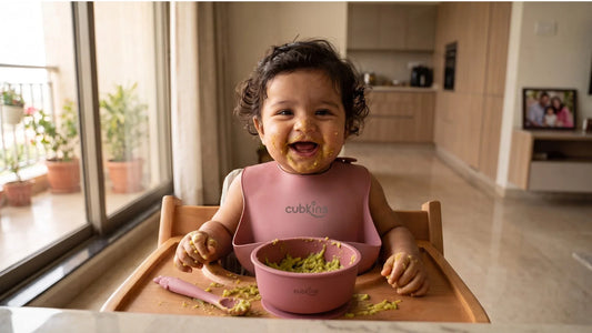 Indian baby wearing a Cubkins raspberry silicone bib with food-catcher pocket