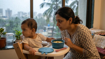 Indian baby turning away from spoon at highchair with raspberry silicone bowl during monsoon weaning — Cubkins