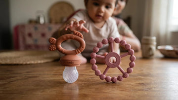Cubkins Fruit Feeder Teether and Silicone Ring Teether side by side on a wooden table