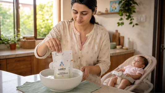 Indian mother safely thawing frozen breast milk in a bowl of warm water on her kitchen counter — the correct method for preserving antibodies
