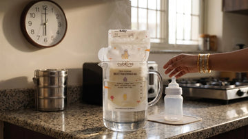 Frozen Cubkins milk storage bag thawing in a jug of warm water — the safe fast method