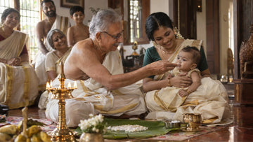 Kerala family at a choroonu ceremony: grandfather touching payasam to a six-month-old baby's lips