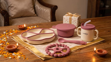 Cubkins feeding set and ring teether wrapped as Diwali gifts beside diyas and marigolds