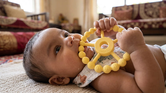 Three-month-old Indian baby drooling and holding a Cubkins Silicone Ring Teether in a whole-fist grip