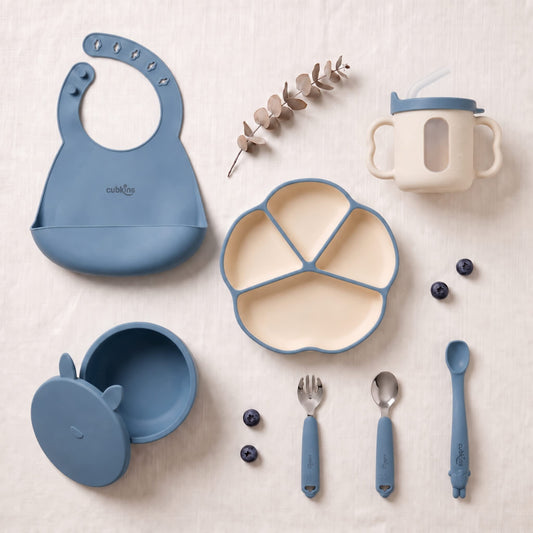 Cubkins 7-piece essential silicone baby feeding set in raspberry pink — bib, 4-compartment suction plate, suction bowl with lid, bendable spoon, steel spoon, steel fork and sensory straw training cup with transparent window laid out flat