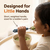 Toddler holding the Cubkins blue olive steel baby spoon in a palmar grasp and eating spinach khichdi