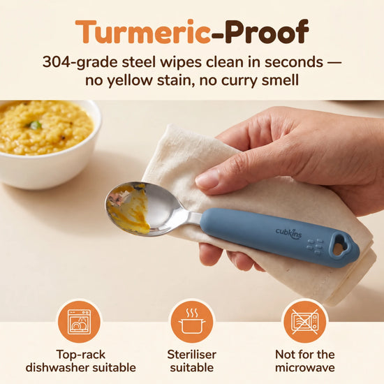 Cubkins 304 steel baby spoon head being wiped clean of turmeric dal, blue olive silicone handle, with care icons for dishwasher, steriliser and no microwave