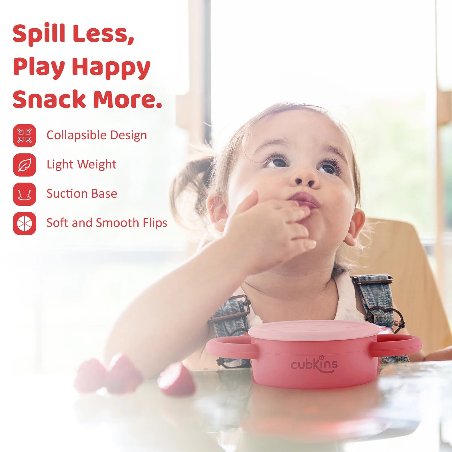 Happy toddler self-feeding from the Cubkins snack cup; features a lightweight design and secure suction base.