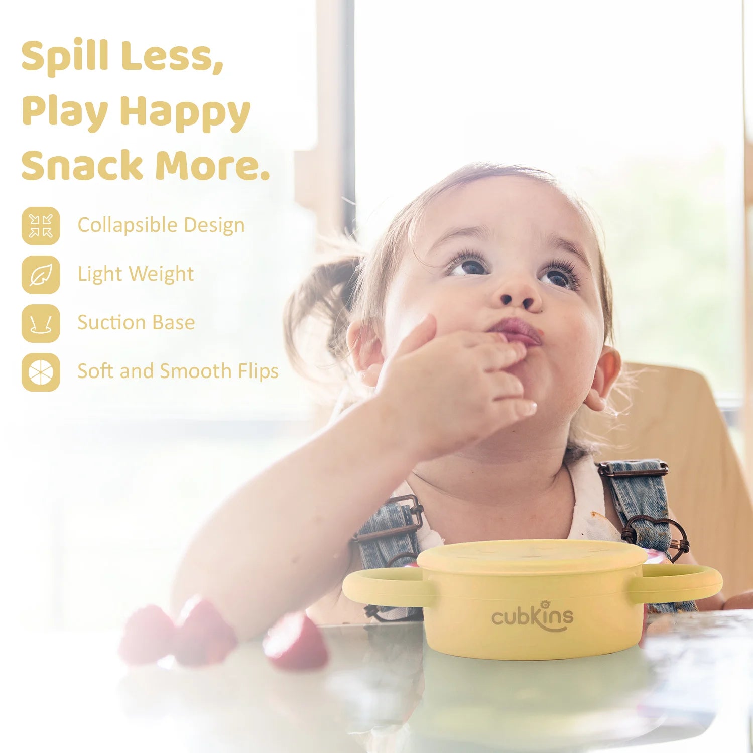 Happy toddler self-feeding from the Cubkins snack cup; features a lightweight design and secure suction base.