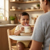 Smiling baby in a high chair drinking from the Cubkins raspberry pink silicone straw training cup while a parent watches in a warm kitchen setting