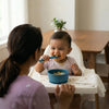 Happy baby self-feeding with Cubkins blue ergonomic spoon and suction bowl in high chair