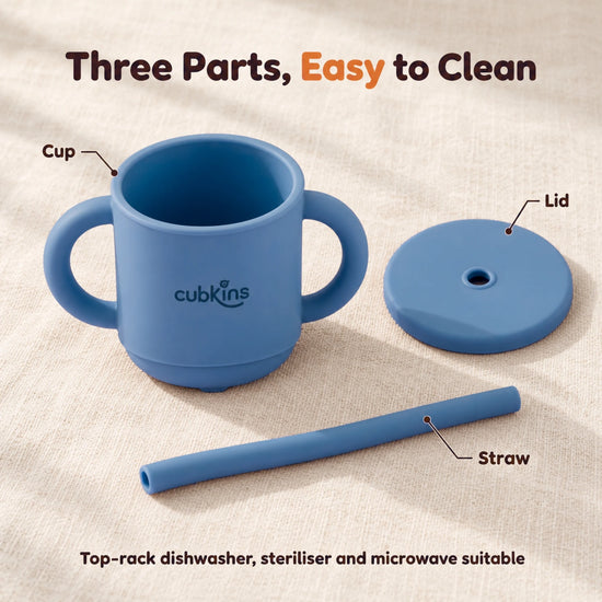 The Cubkins blue olive straw cup taken apart into cup, lid and straw on a cream linen surface