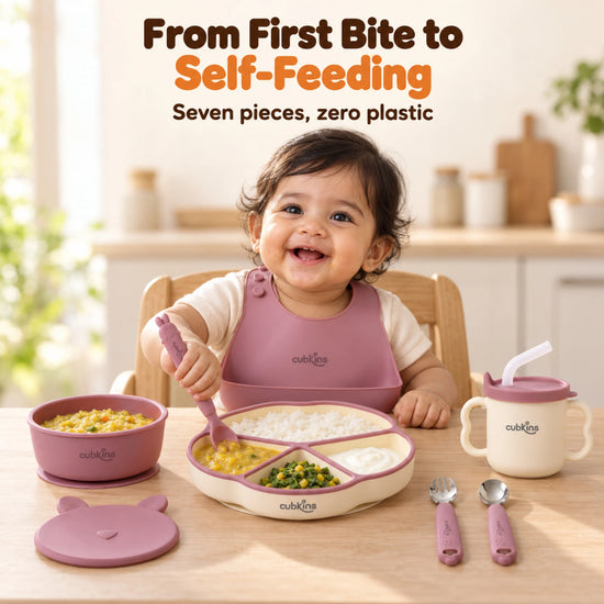 Indian baby at the table with the Cubkins Raspberry 7-piece feeding set: bib, plate, bowl, bunny lid, sensory straw cup, spoons and fork