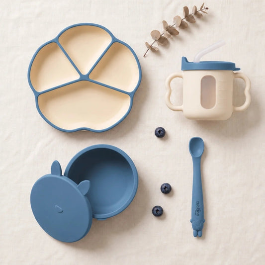 Cubkins complete feeding set of 4 in Blue Olive: silicone suction plate, suction bowl with bunny storage lid, sensory straw training cup and Smart-Bend spoon, top-down on linen