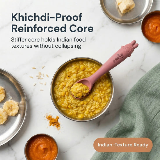 Cubkins raspberry silicone baby spoon resting in a steel bowl of khichdi, surrounded by Indian baby first foods including banana, dal, and turmeric on a marble surface