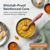 Cubkins raspberry silicone baby spoon resting in a steel bowl of khichdi, surrounded by Indian baby first foods including banana, dal, and turmeric on a marble surface