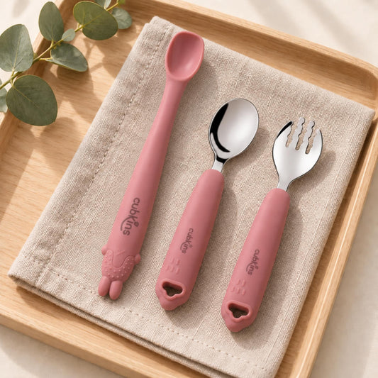 Cubkins raspberry self-feeding set of 3: Smart-Bend bendable silicone spoon, 304 steel spoon and steel fork on a linen napkin on a wooden tray