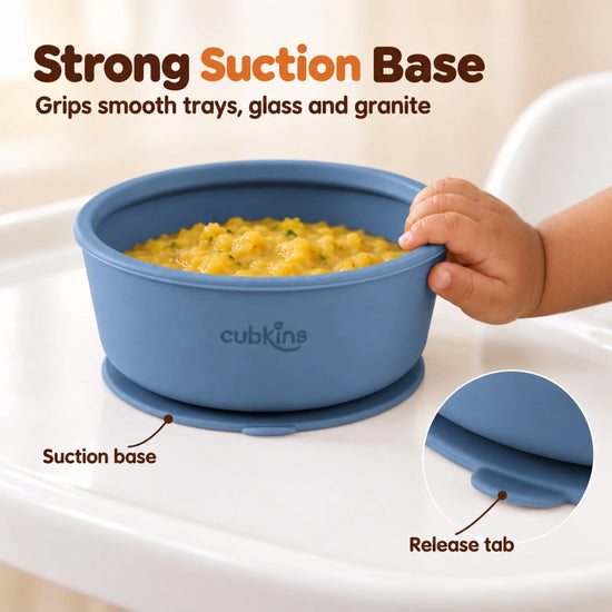 Baby hand pushing the Cubkins blue olive silicone suction bowl sideways on a high chair tray while the suction base holds it in place