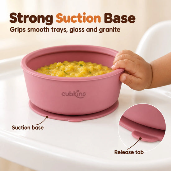 Baby hand pushing the Cubkins raspberry silicone suction bowl sideways on a high chair tray while the suction base holds it in place