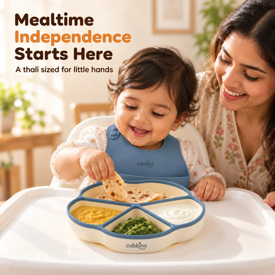 Indian mother smiling as her baby feeds himself from the Cubkins blue olive silicone suction plate on a high chair