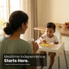 Indian mother watching her baby self-feed happily from raspberry Cubkins silicone suction plate on highchair — mealtime independence lifestyle photo