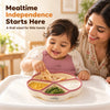 Indian mother smiling as her baby feeds himself from the Cubkins raspberry silicone suction plate on a high chair