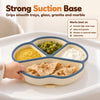 Baby hand pulling at the edge of the Cubkins blue olive silicone suction plate while the suction base holds it to the high chair tray
