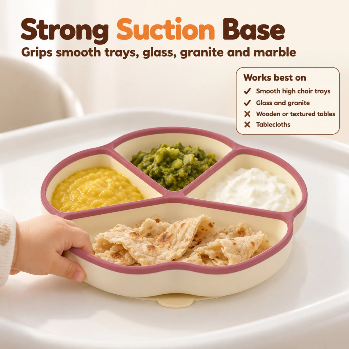 Baby hand pulling at the edge of the Cubkins raspberry silicone suction plate while the suction base holds it to the high chair tray