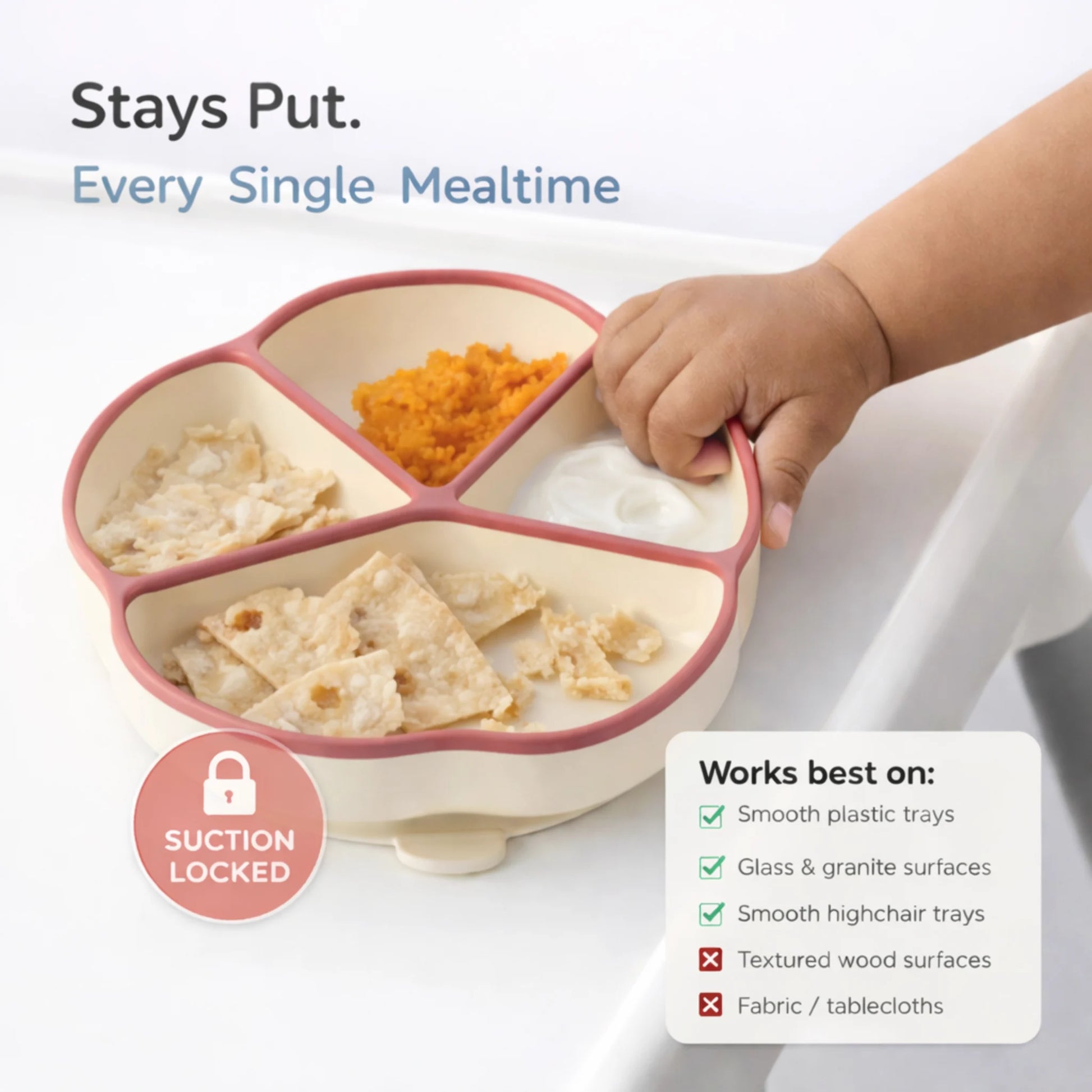 Baby trying to lift raspberry Cubkins suction plate while it stays locked to highchair tray — suction base holds firm on smooth plastic surfaces