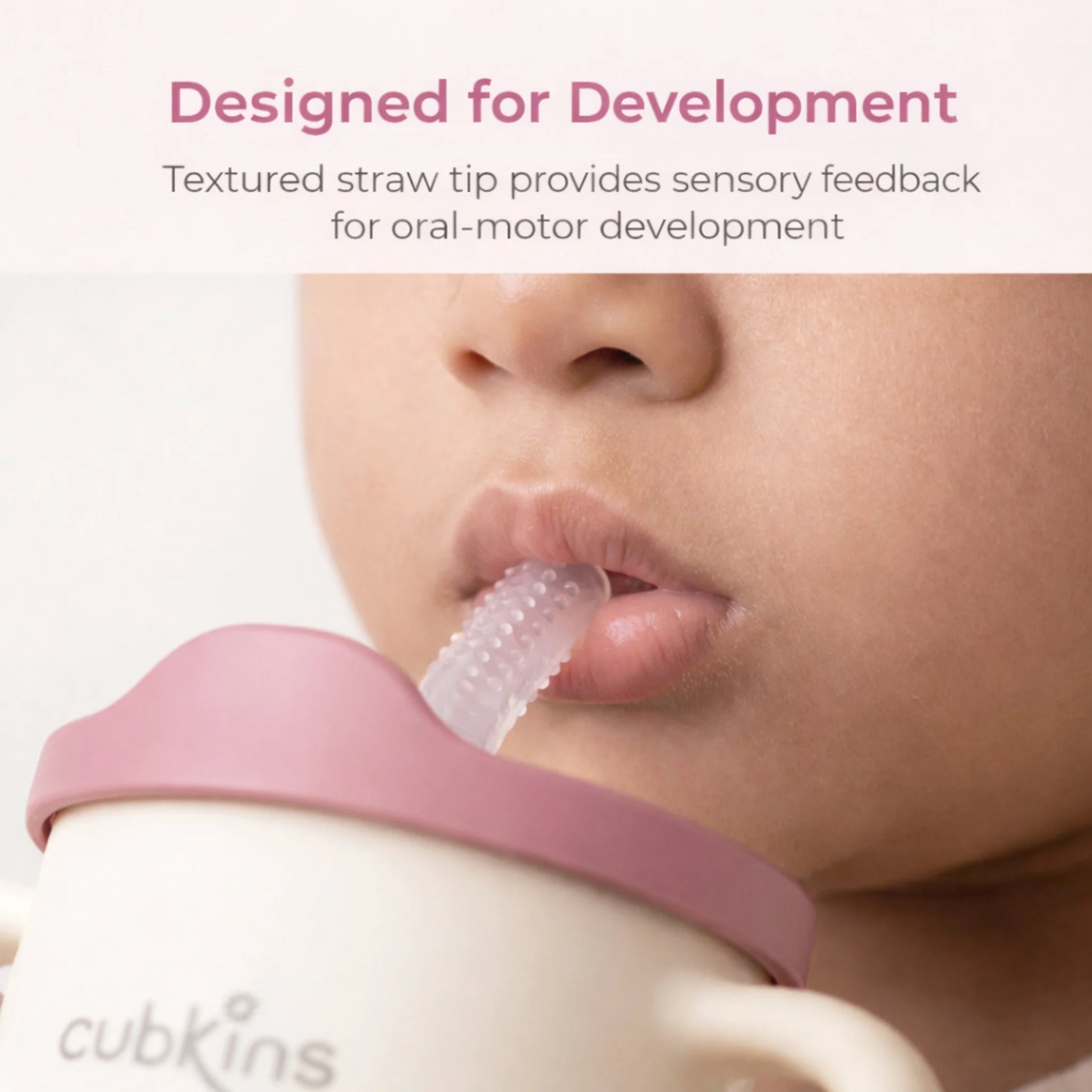 Close-up of a baby using the Cubkins textured silicone sensory straw with raspberry pink lid, designed to provide sensory feedback for oral-motor development