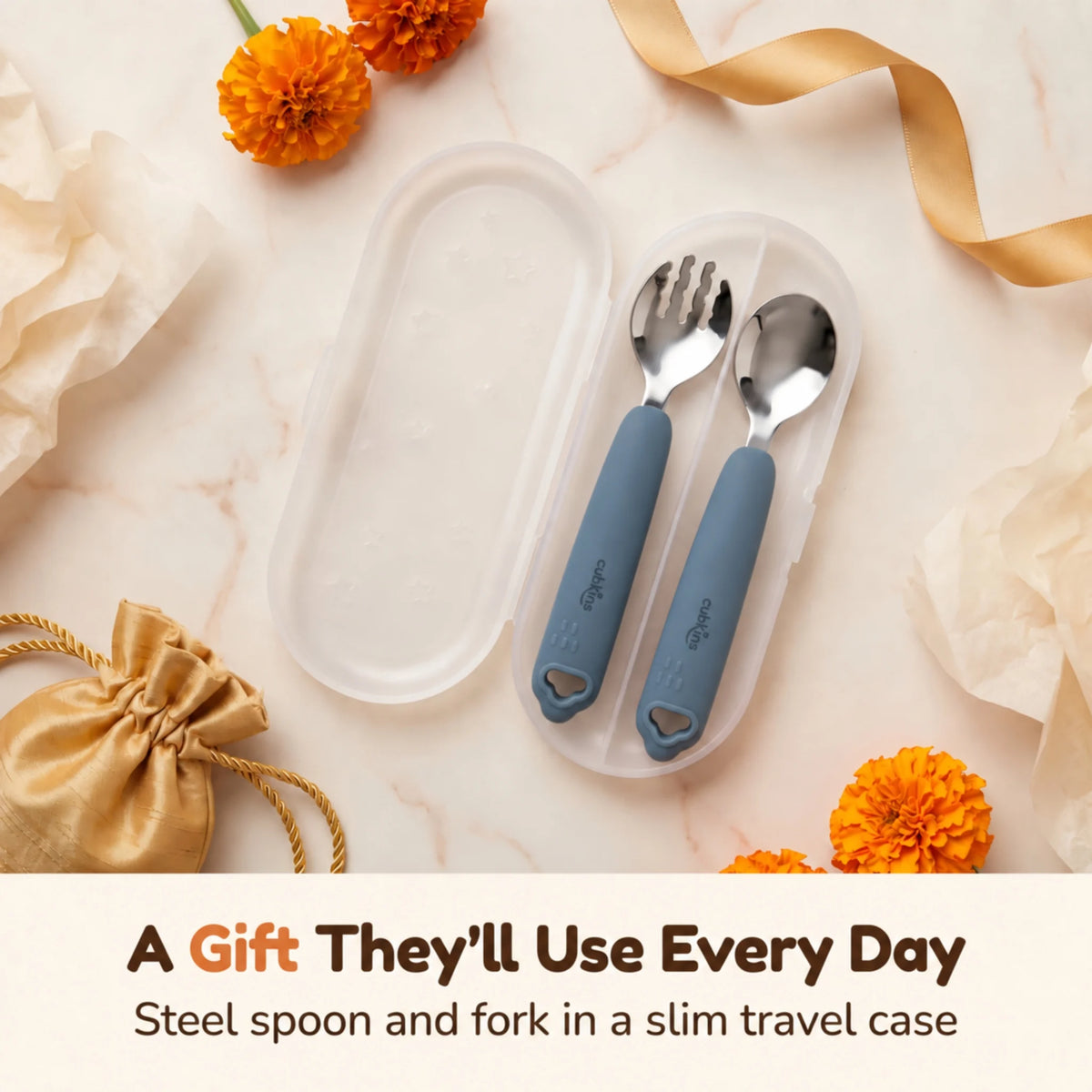 Cubkins blue olive steel toddler spoon and fork in an open travel case, styled as a gift with marigolds, gold ribbon and a silk potli pouch