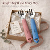 Both Cubkins toddler forks in Raspberry and Blue Olive presented together in a kraft gift box with tissue paper and a handwritten tag reading "For little ones," with a silk ribbon and eucalyptus sprig, and the caption "A Gift They'll Use Every Day – Available in Raspberry and Blue Olive"
