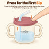 Illustration of a fingertip pressing the air-vent hole on the raspberry lid of the Cubkins straw training cup, pushing the drink up the straw