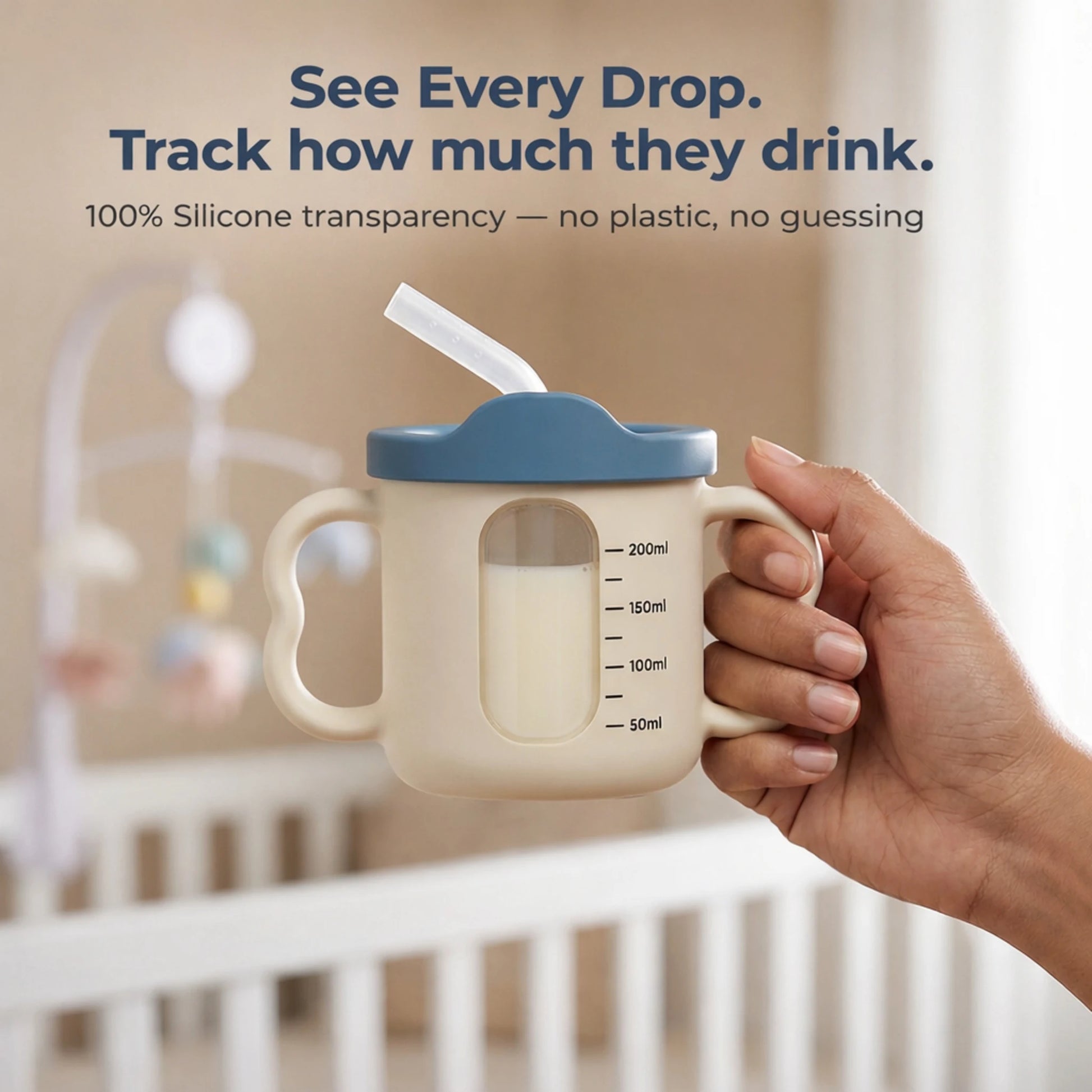 Adult hand holding the Cubkins blue silicone straw training cup showing the transparent window with measurement markings from 50ml to 200ml to track how much baby drinks