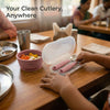 Toddler reaching into an open Cubkins raspberry cutlery travel case at a restaurant table next to a silicone suction bowl with fruit