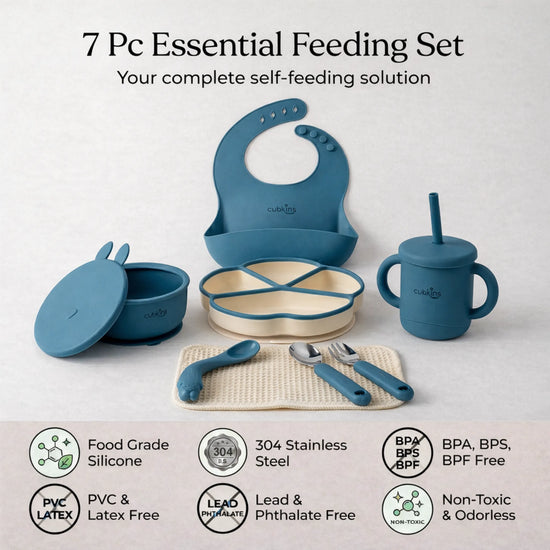 Flatlay of the complete Cubkins blue 7-piece Essential Feeding Set — silicone bib, divided suction plate, suction bowl with bunny lid, straw sippy cup, waffle muslin cloth, and stainless steel spoon and fork — with safety certification icons: Food Grade Silicone, 304 Stainless Steel, BPA/BPS/BPF Free, PVC & Latex Free, Lead & Phthalate Free, Non-Toxic & Odorless.