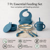 Flatlay of the complete Cubkins blue 7-piece Essential Feeding Set — silicone bib, divided suction plate, suction bowl with bunny lid, straw sippy cup, waffle muslin cloth, and stainless steel spoon and fork — with safety certification icons: Food Grade Silicone, 304 Stainless Steel, BPA/BPS/BPF Free, PVC & Latex Free, Lead & Phthalate Free, Non-Toxic & Odorless.