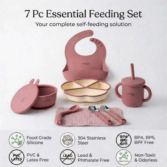 Flatlay of the complete Cubkins raspberry 7-piece Essential Feeding Set — silicone bib, divided suction plate, suction bowl with bunny lid, straw sippy cup, waffle muslin cloth, and stainless steel spoon and fork — with safety certification icons: Food Grade Silicone, 304 Stainless Steel, BPA/BPS/BPF Free, PVC & Latex Free, Lead & Phthalate Free, Non-Toxic & Odorless.