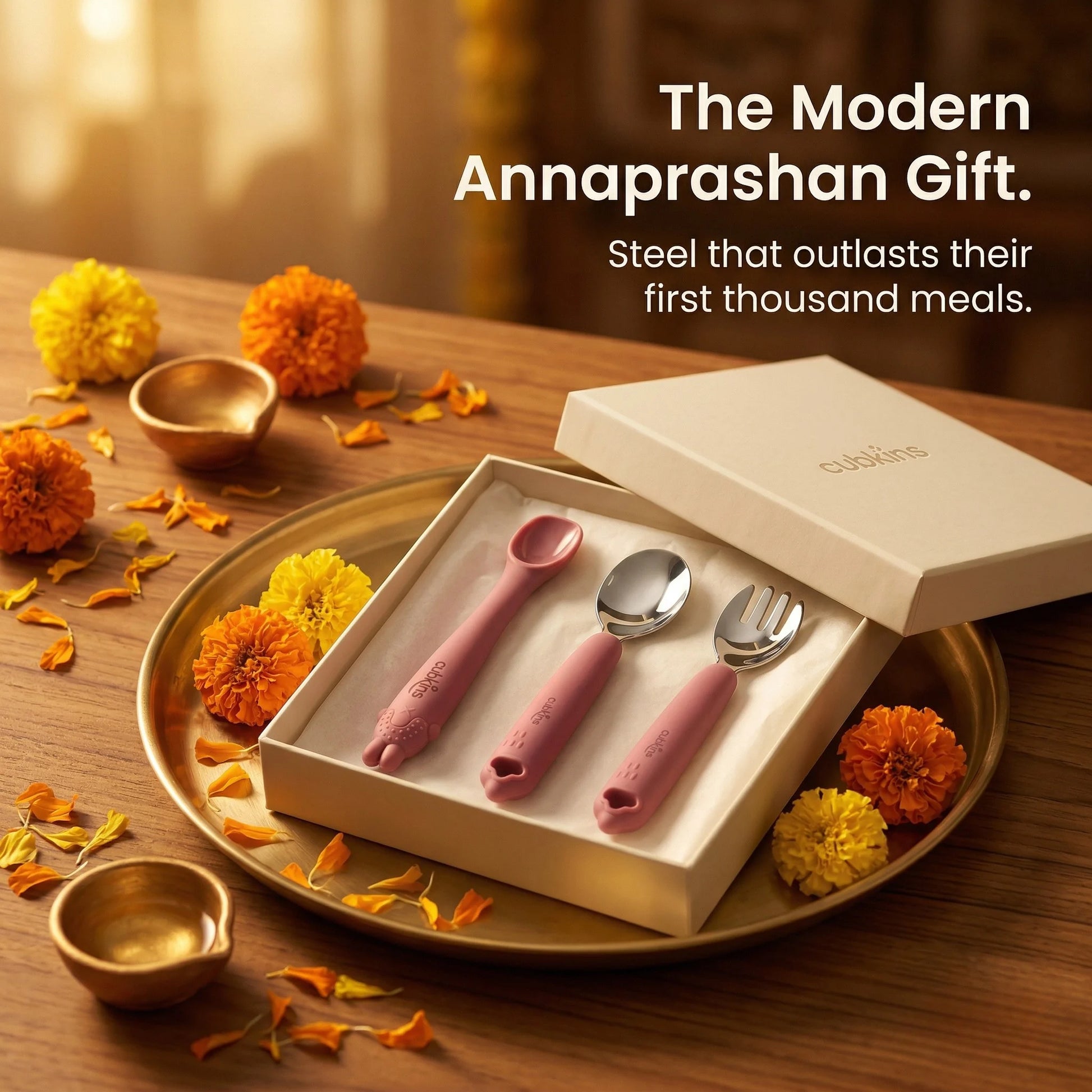 Cubkins 3-piece baby cutlery set in raspberry presented as a modern Annaprashan gift – gift box on brass thali with diyas and marigold flowers, premium steel baby feeding set