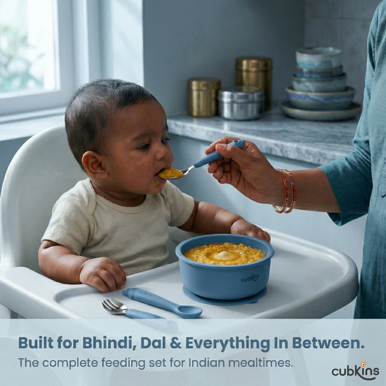 Indian mother feeding baby dal khichdi in high chair using Cubkins blue stainless steel spoon – complete feeding set for Indian mealtimes