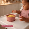 Baby in pink bib eating from Cubkins raspberry silicone suction bowl on highchair tray showing fits most highchairs feature