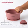 Close-up of Cubkins raspberry silicone bowl showing strong suction base gripping smooth surface with easy adult release tab